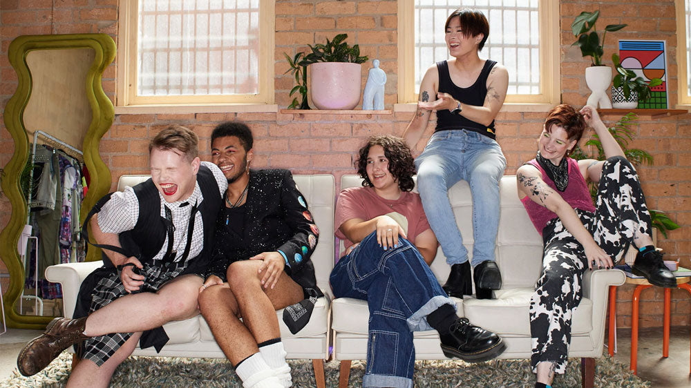 Group of gender diverse people laughing on a couch