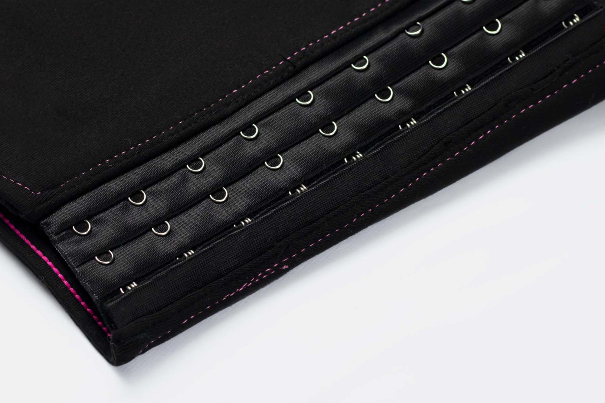 Black satin waist trainer with silver metal hooks and pink stitching for safe comfortable chest compression binding.