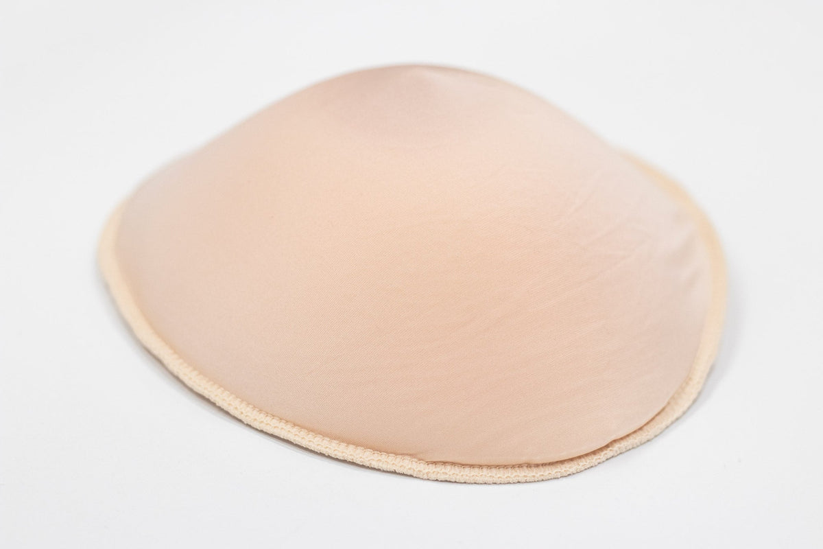 Beige silicone breast form cover with smooth rounded surface and stitched edge for comfortable wear