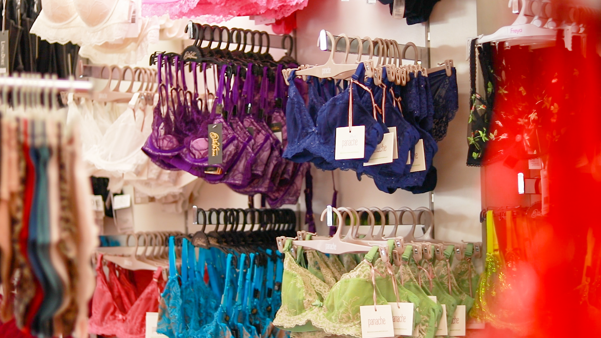 Purple, blue, and green lace lingerie set with intricate detailing and a delicate, feminine design in a lingerie store.