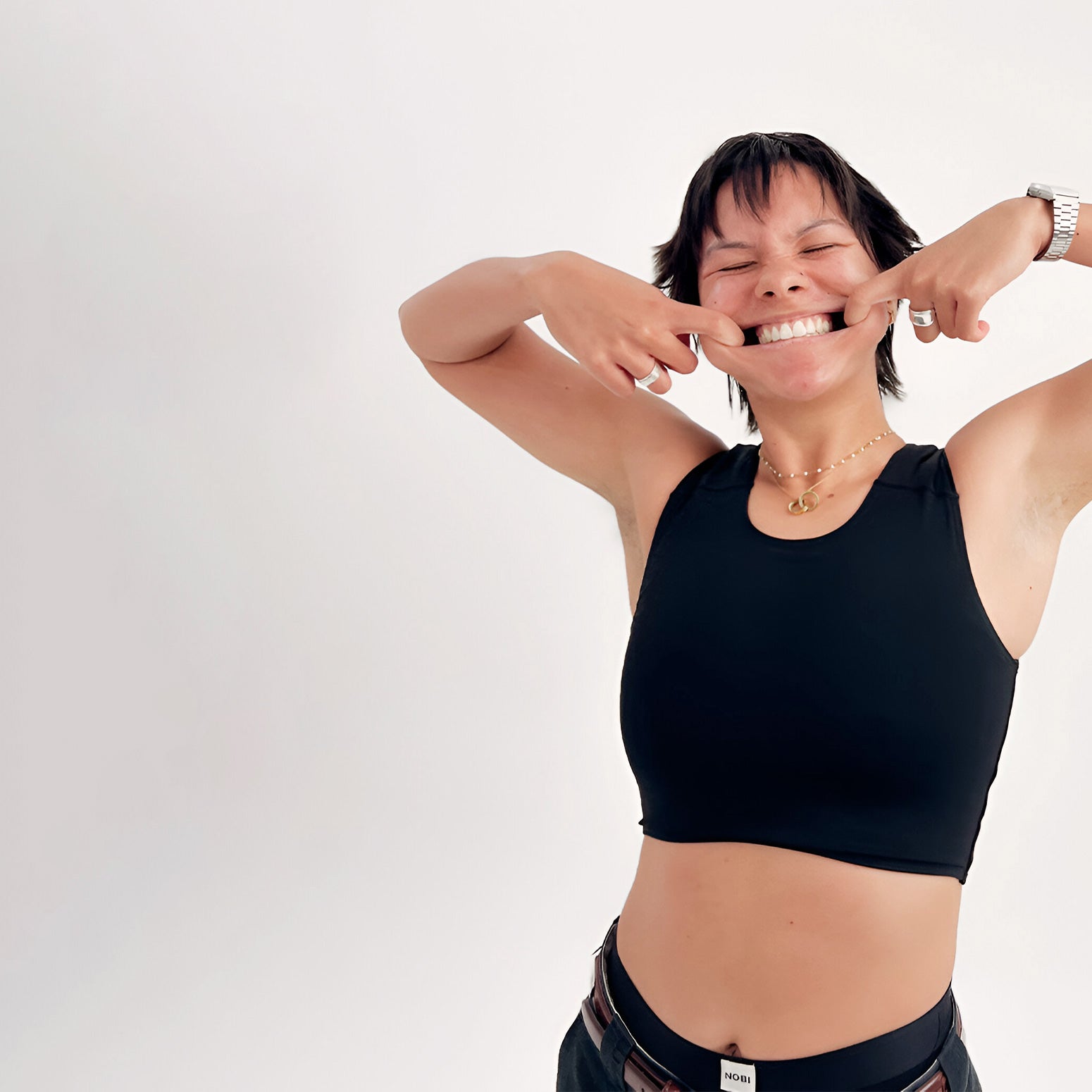 Person wearing a black chest binder and pulling mouth to show teeth