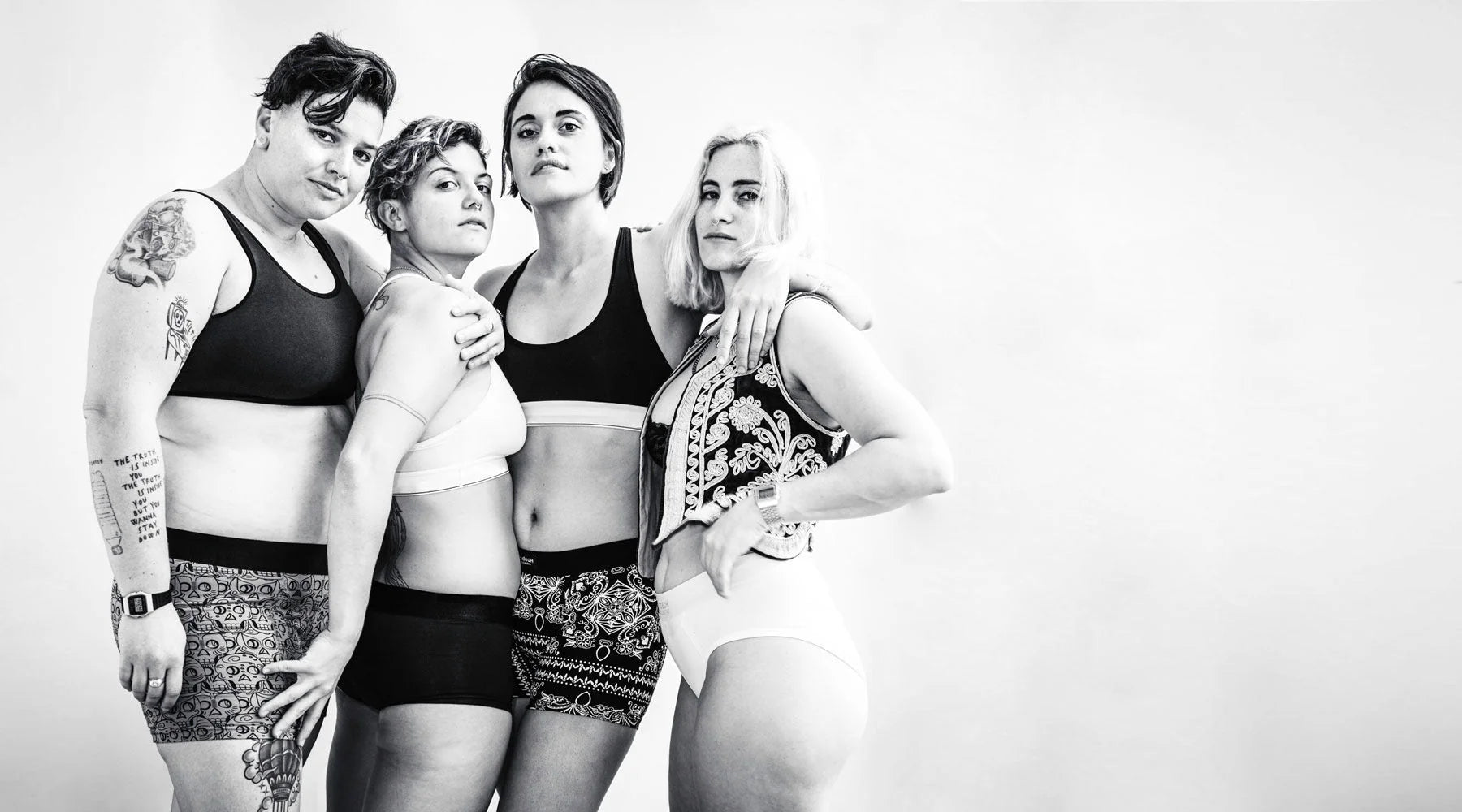 Four people in athletic wear pose together against a plain background.